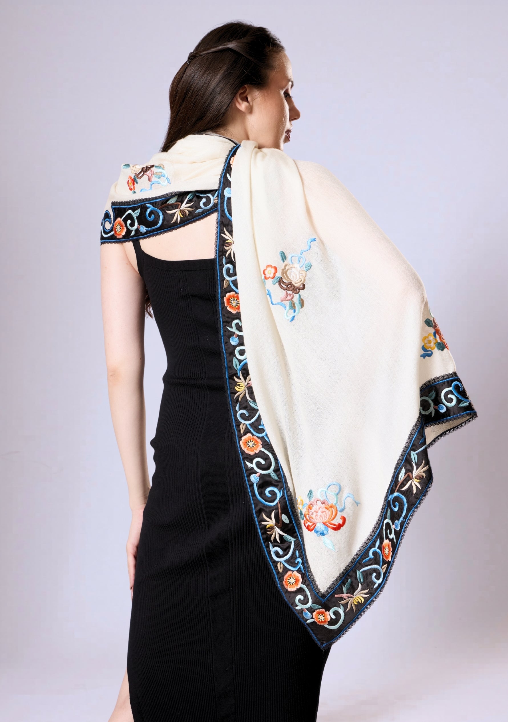 Woman wearing a black dress with an embroidered white shawl draped over her shoulders.