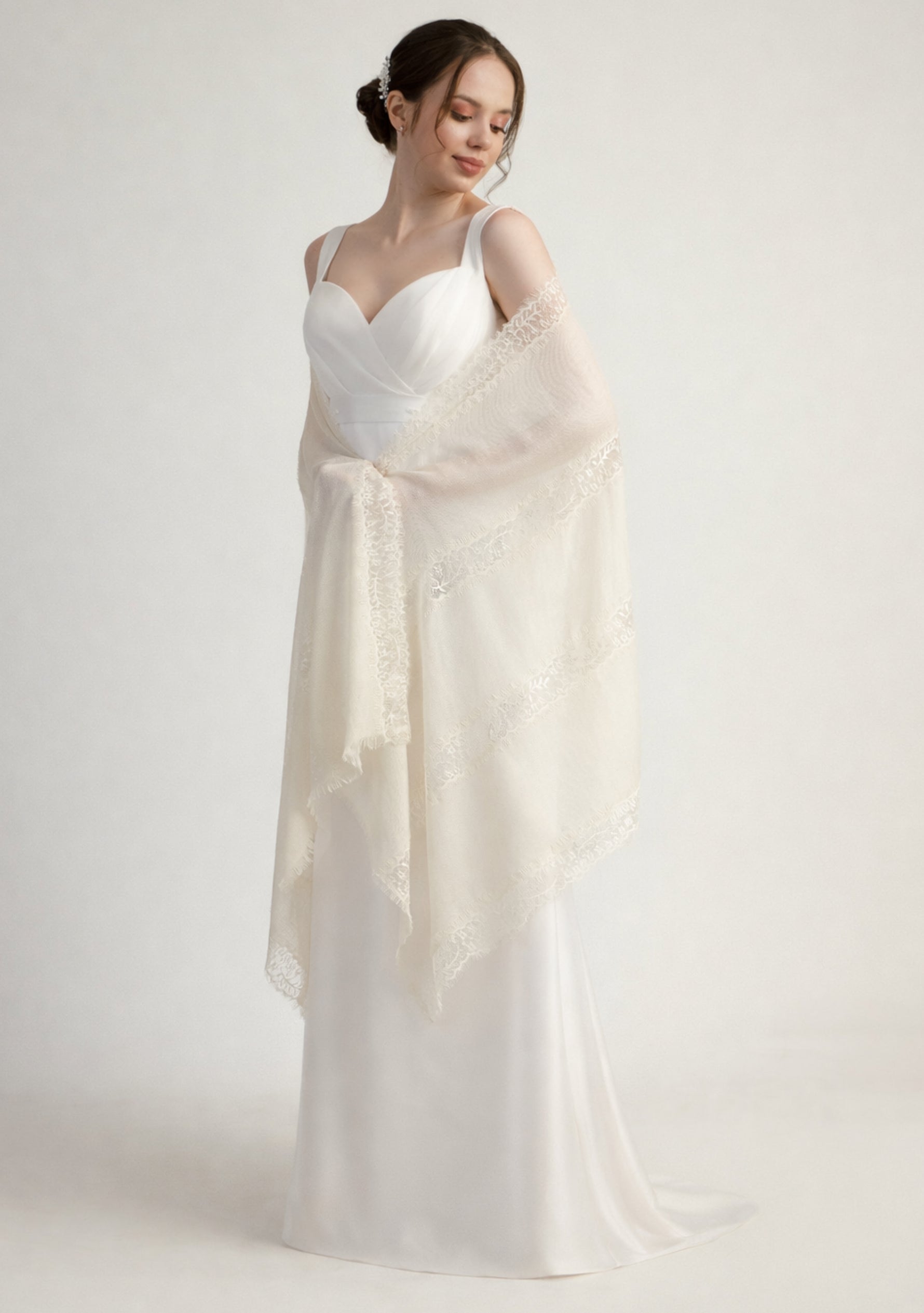 Woman wearing a white dress with a Maneesha Ruia Bridal Ivory shawl on a plain background