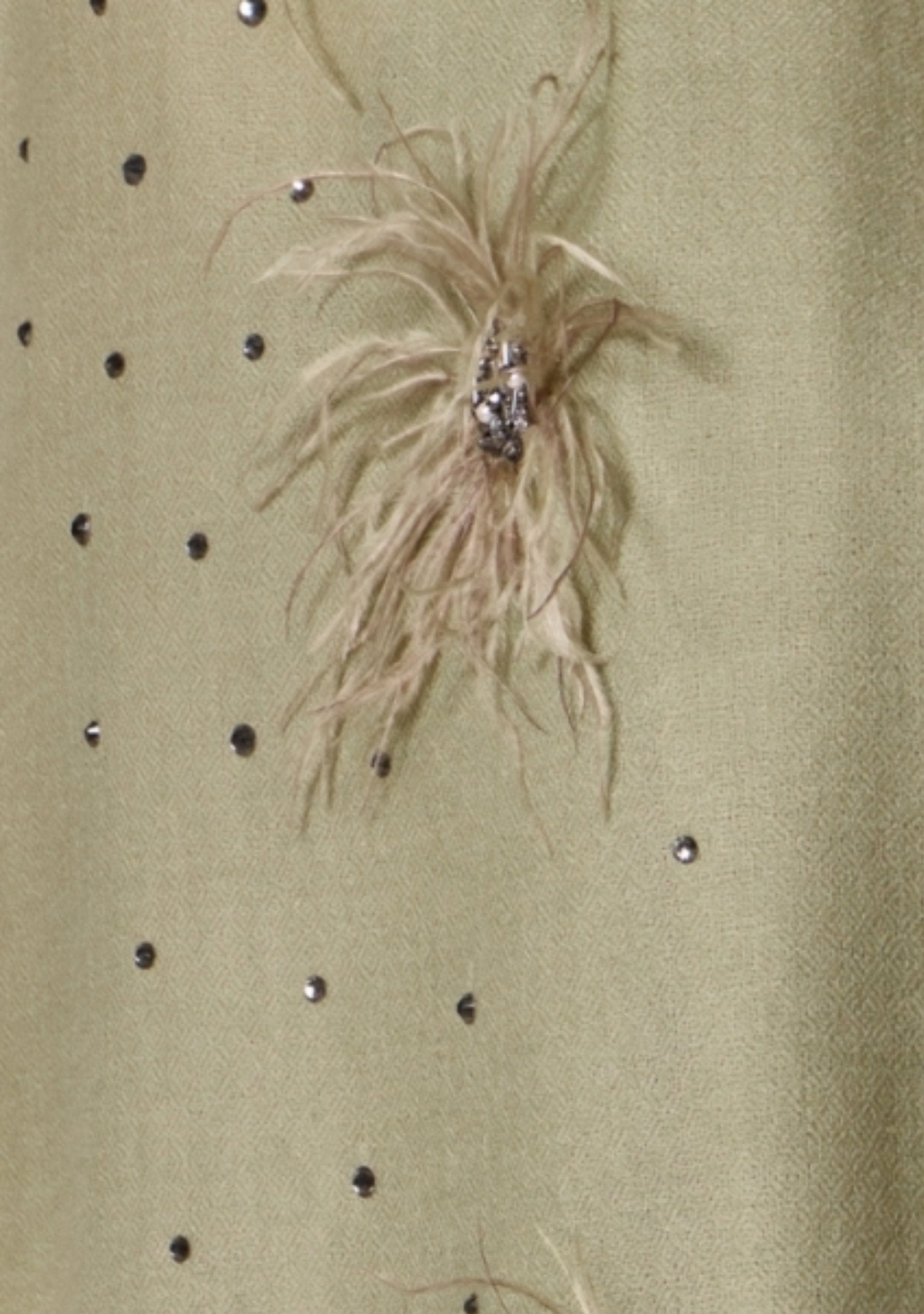 Close-up of a shawl surface decorated with scattered silver rhinestones and a central feather embellishment with a metallic embroidery and swarovski crystals