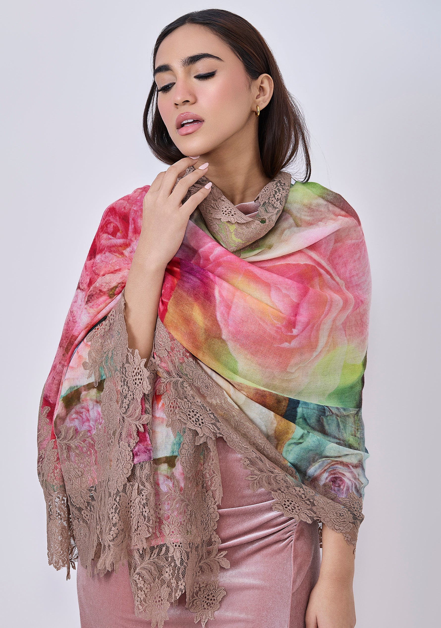 A woman wearing a multicolored scarf with a floral pattern and sienna-colored lace border.