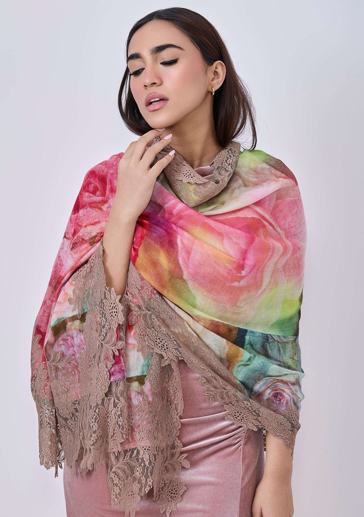 A woman wearing a multicolored scarf with a floral pattern and sienna-colored lace border.