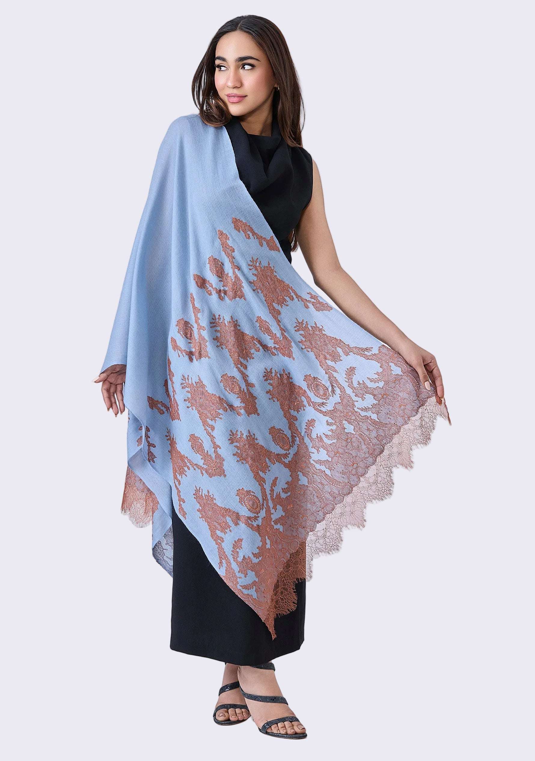 Woman holding a Maneesha Ruia Steel Blue Cashmere Scarf — mocha mousse filigree lace appliqué on luxuriously soft cashmere against a white background