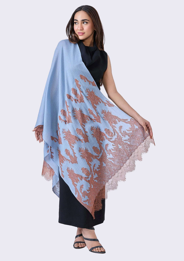Woman holding a Maneesha Ruia Steel Blue Cashmere Scarf — mocha mousse filigree lace appliqué on luxuriously soft cashmere against a white background