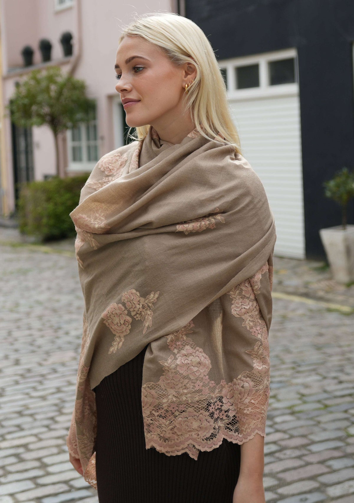 A woman wearing a natural color cashmere scarf with dual shade copper Chantilly lace, draped around her neck.