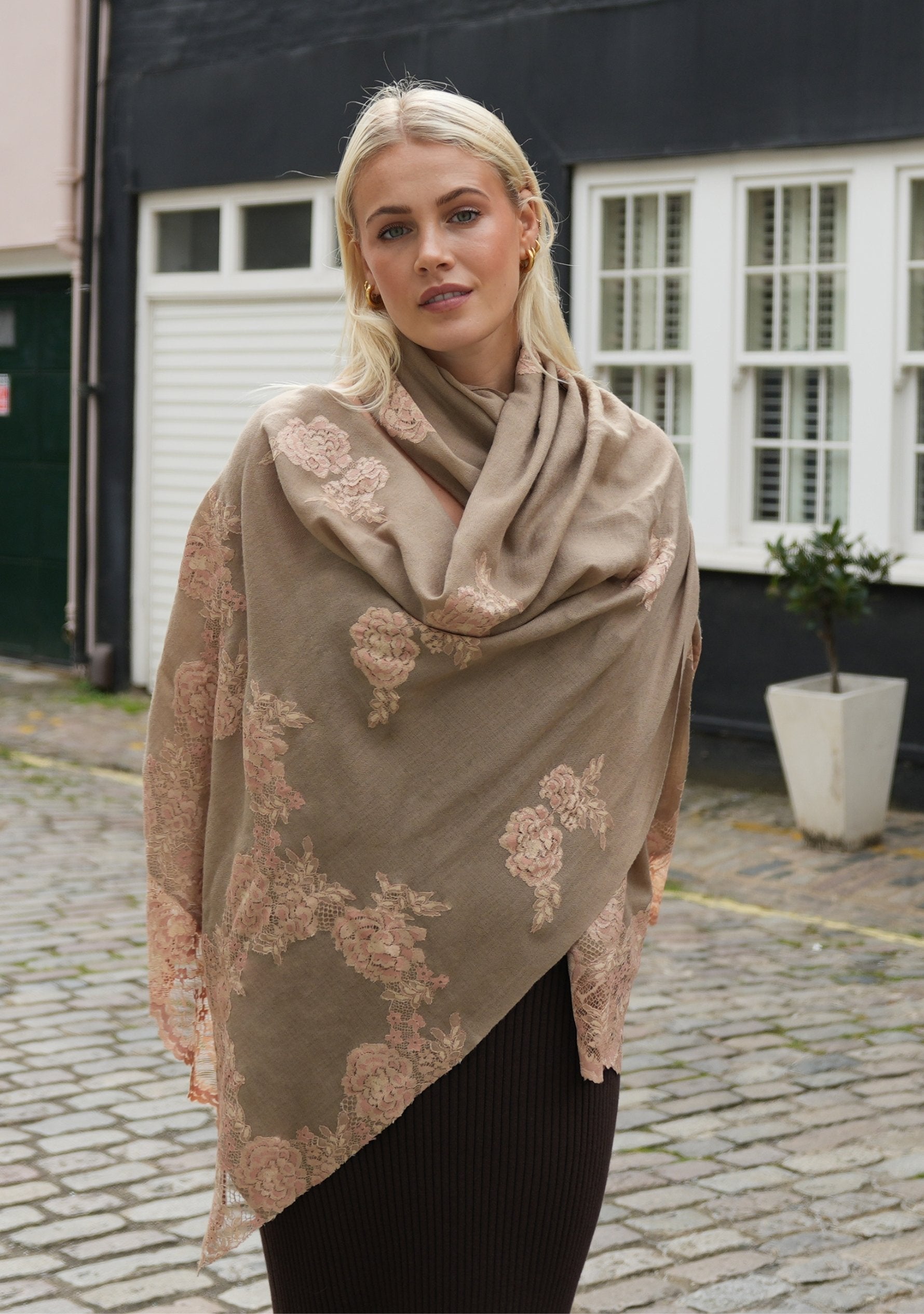 A woman wearing a natural color cashmere scarf with dual shade copper Chantilly lace, draped around her neck.