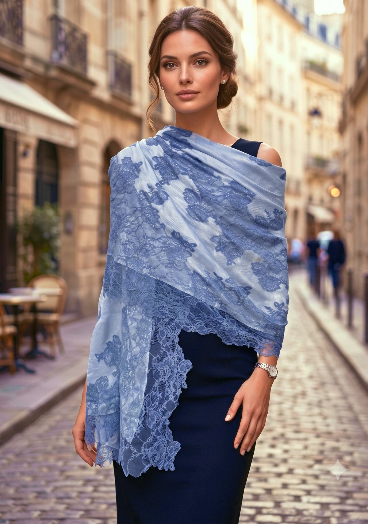 A woman standing on a cobblestone street wearing a light blue and white lace-patterned shawl draped over a dark navy dress.