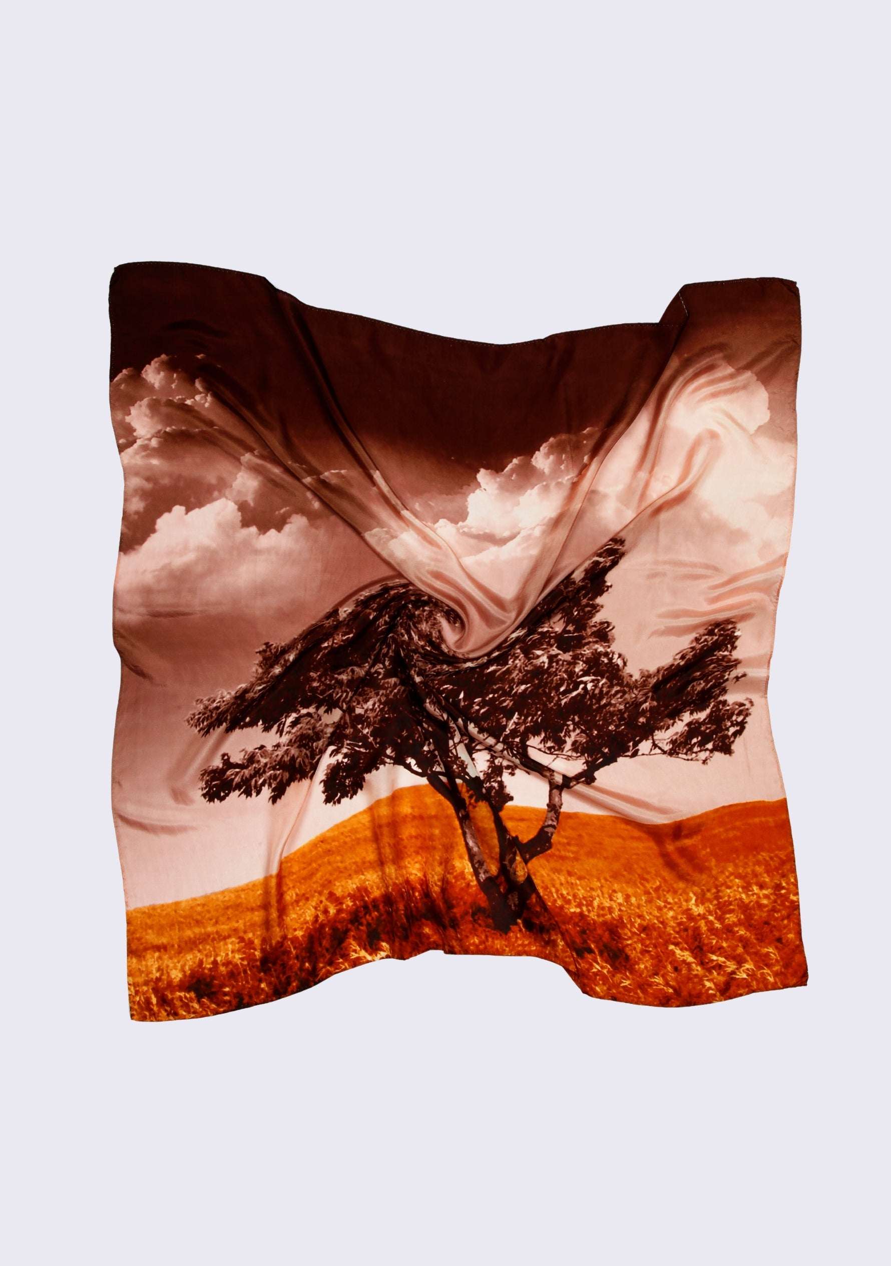 Santa Cruz Print Silk Square Scarf by Maneesha Ruia featuring a scenic coastal landscape print with a windswept tree, warm rust orange fields, blush pink sky, deep brown clouds, and black accents on luxurious 100% silk.