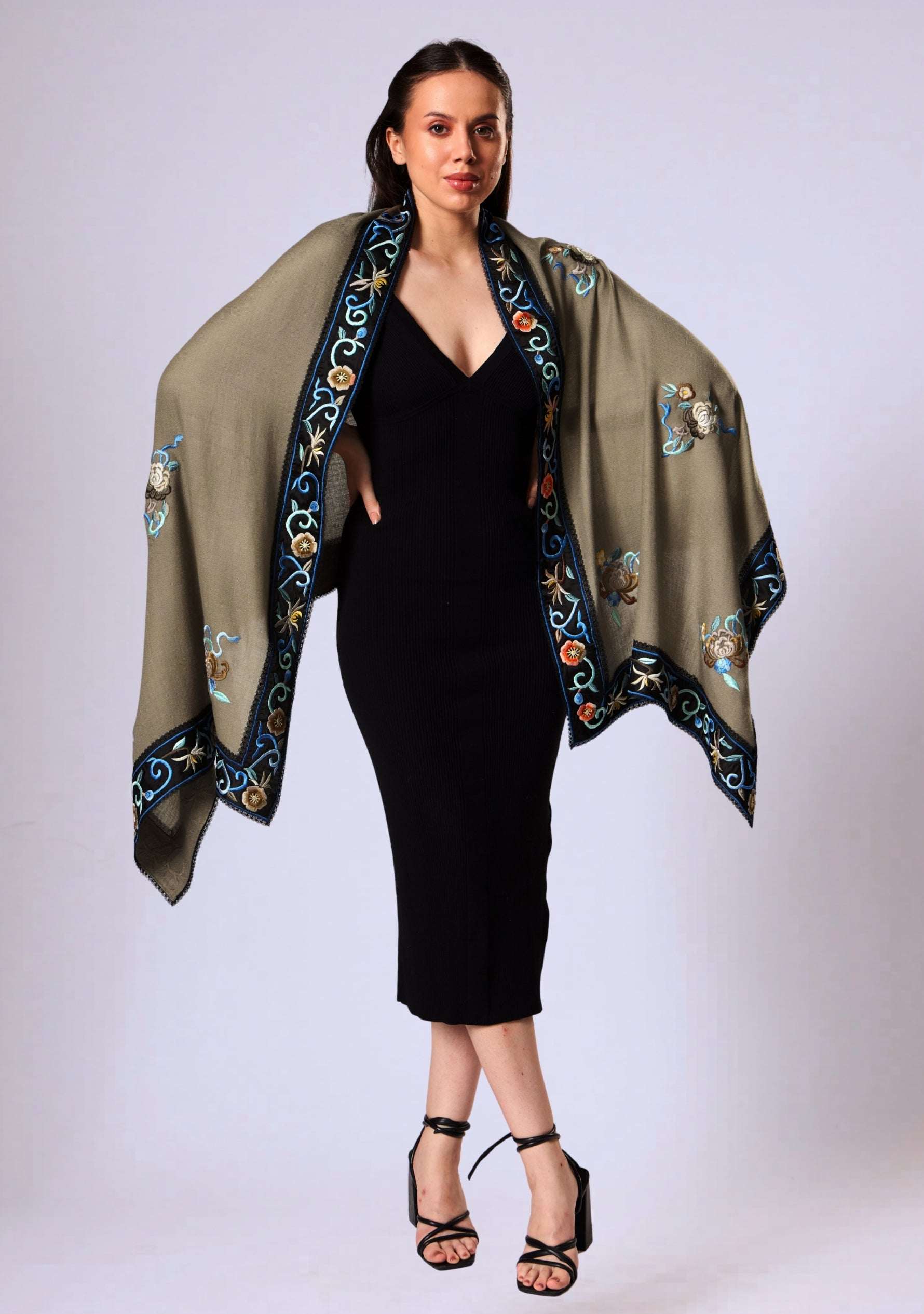 Woman wearing a black dress with an embroidered taupe shawl on a white background