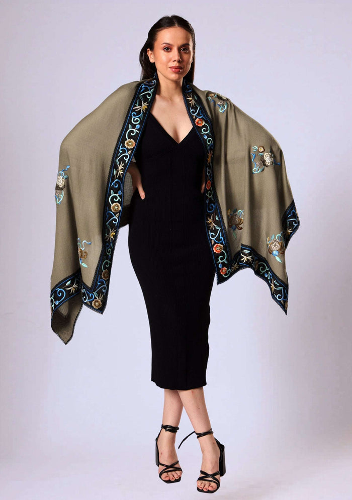 Woman wearing a black dress with an embroidered taupe shawl on a white background