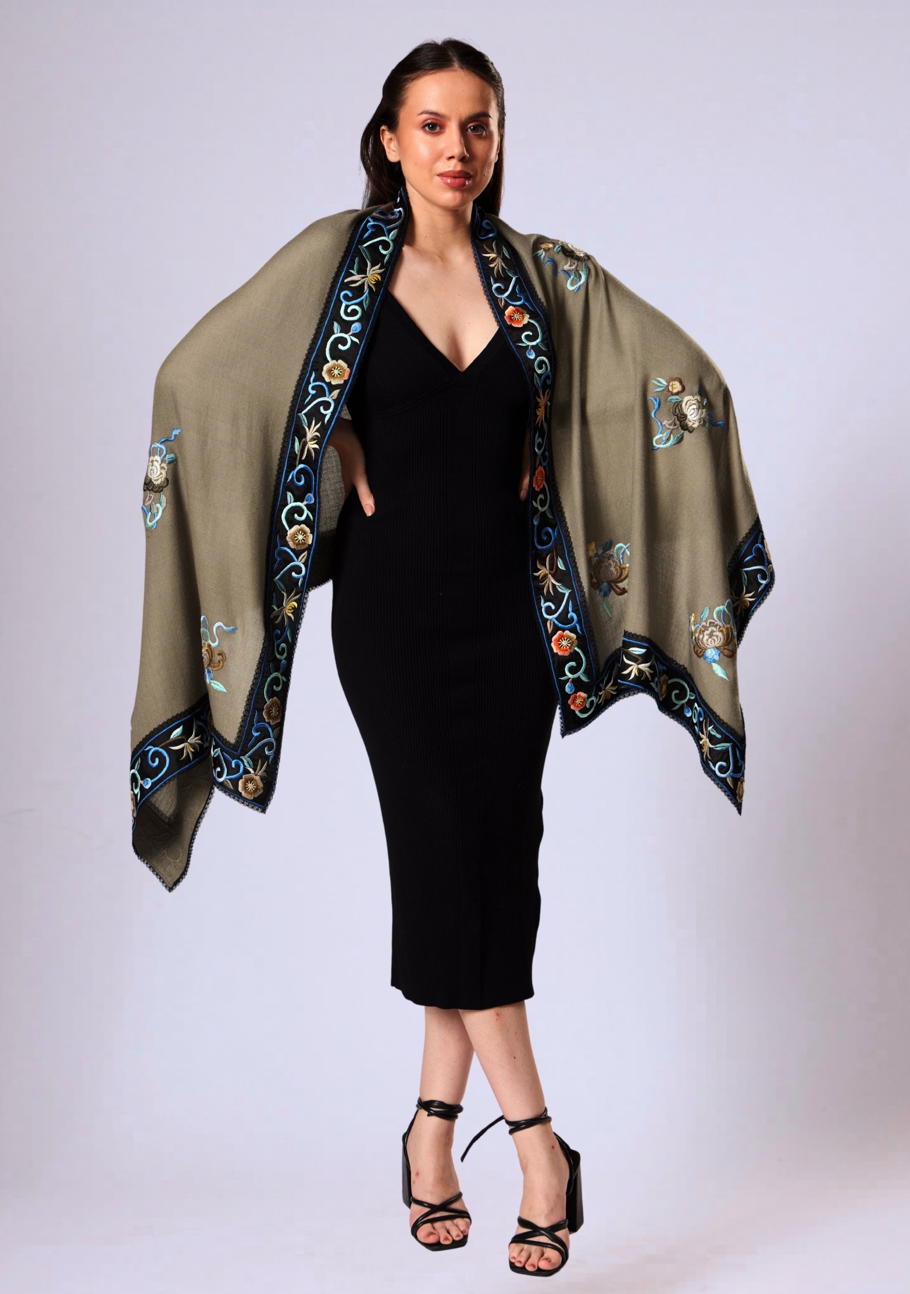 Woman wearing a black dress with an embroidered taupe shawl on a white background