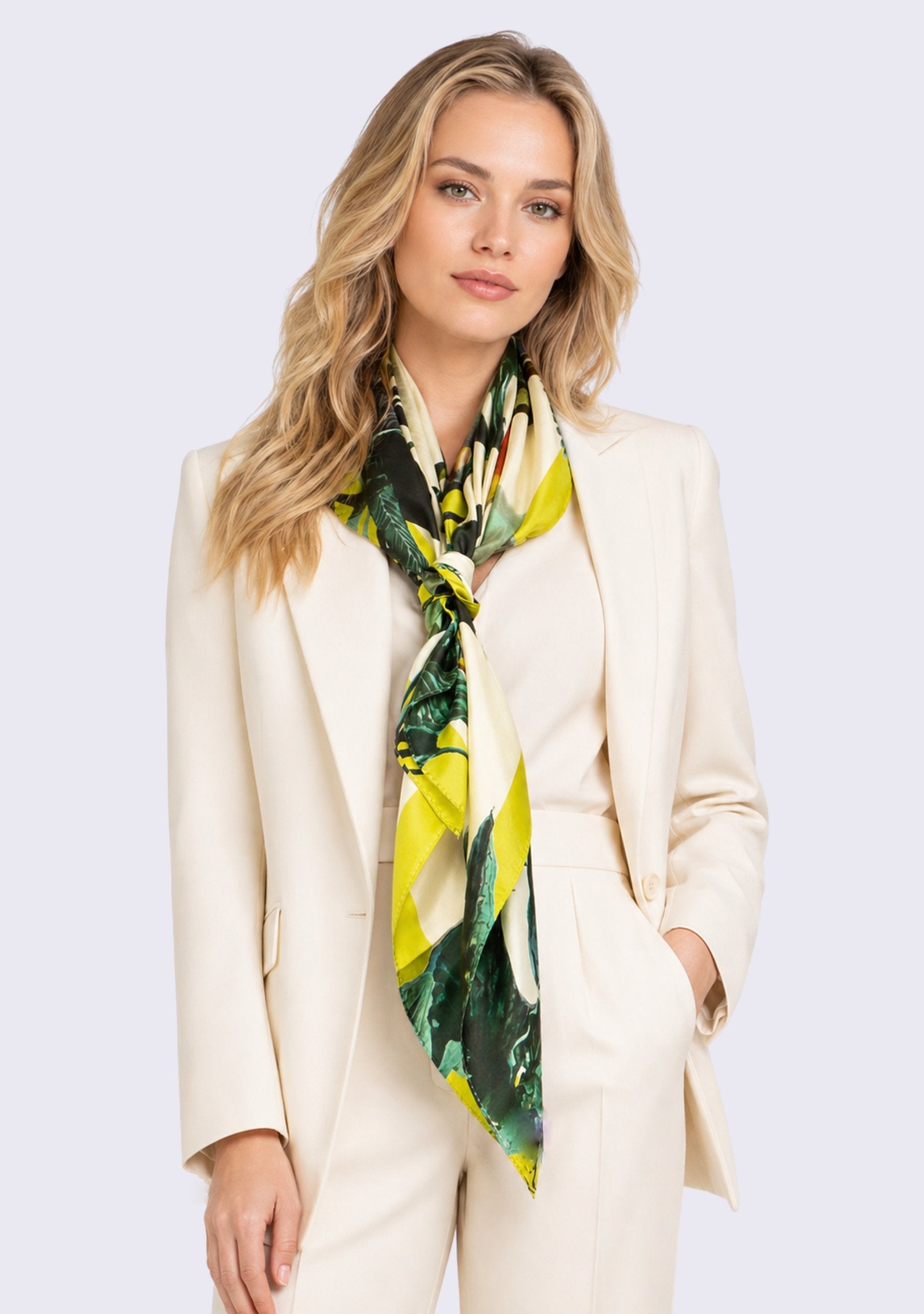 Toucan Print Silk Square Scarf by Maneesha Ruia elegantly tied around the neck, featuring vibrant tropical foliage, exotic toucan motifs, lush emerald green leaves, lime green accents, and ivory tones on luxurious 100% silk.
