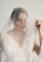 Woman wearing a white wedding dress with a veil against a plain background